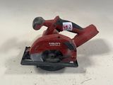 une scie circulaire rouge posée sur une table blanche