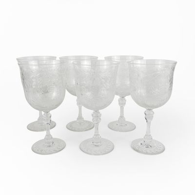 six verres à vin transparents posés les uns à côté des autres sur une surface blanche