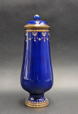 an antique blue vase with gold trimming and a lid