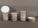 a stack of silver and white plates with blue rims