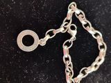 a close up of a silver chain bracelet on a black surface