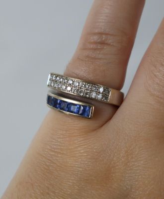 la main d'une femme tenant une bague sertie d'un diamant et d'un saphir