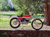 a red motorcycle parked on a stone wall by a tree