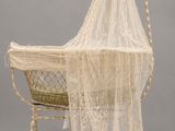 un berceau à l'ancienne avec un baldaquin en dentelle blanche et un panier en osier