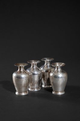 four silver vases sitting on top of a black surface