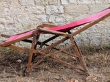 a pink chair that is sitting in front of a stone wall