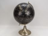 un globe noir et doré posé sur une table blanche