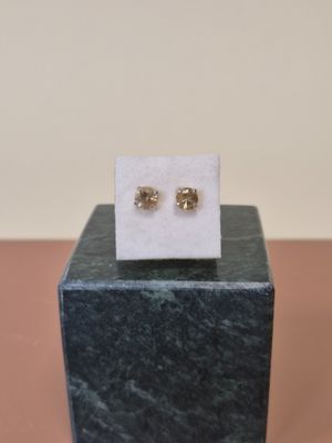 une paire de boucles d'oreilles en or posée sur un bloc de marbre