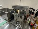 un plan de travail en acier inoxydable dans une cuisine professionnelle, sur lequel sont posées de nombreuses bouteilles