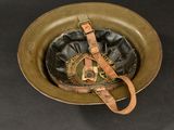 an old military helmet with a leather band and a metal buckle