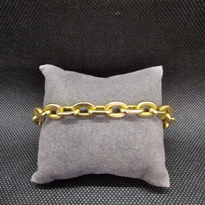 gros plan d'un bracelet en chaîne en or sur un oreiller