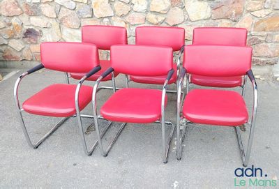quatre fauteuils en cuir rouge disposés devant un mur de pierre
