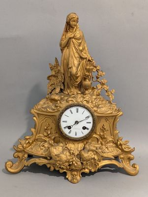 une horloge en or surmontée d'une statue
