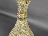 an old brass vase sitting on top of a gray surface