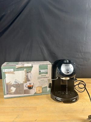 the coffee maker is sitting on the table next to the box