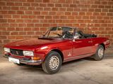 an image of a red convertible car parked in front of a brick wall