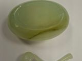 a green bowl with a spoon in it on a white surface
