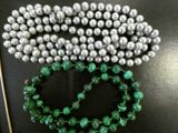 two strands of green and silver beads on a black surface