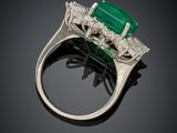 an emerald and diamond ring on a black surface