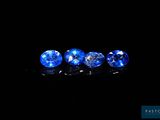 a group of three blue sapphires on a black surface