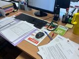 un bureau sur lequel se trouvent un ordinateur et beaucoup de papiers