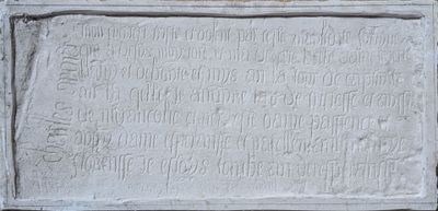 une vieille plaque en pierre portant une inscription, devant un mur de briques