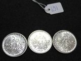 three silver coins sitting next to each other on a black surface