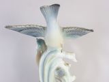 a white vase with a bird on top of it