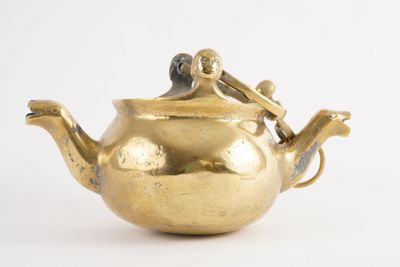 une théière en or ornée d'un oiseau