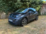 La BMW i3 est garée devant un mur de pierre