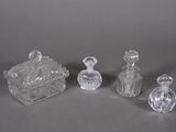 three clear glass bottles and a small glass box on a gray surface
