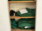 many green shirts on a shelf in a closet