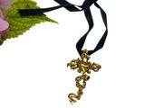 une croix en or sur un ruban noir, avec une fleur en arrière-plan