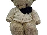 a teddy bear that is wearing a sweater and a bow tie