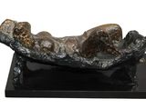 sculpture of a woman laying on a log on a black base