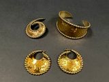 three pieces of gold jewelry sitting on top of a table