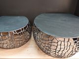 pair of round metal side tables on a wooden stand