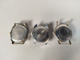 three watches sitting on top of a white surface next to each other