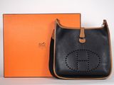 a black and tan handbag with an orange box in the background