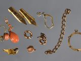 une photo représentant une collection de bijoux en or posés sur une surface grise