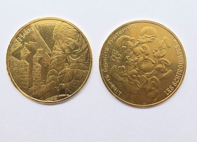 deux pièces d'or posées sur une surface blanche ; l'une représente un homme et l'autre une femme