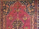un tapis ancien avec un fond rose et un motif sur le bas