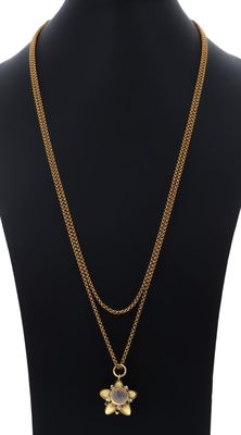 un collier en or avec un pendentif en forme de fleur sur un mannequin