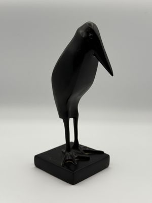 statue of a black bird on a black base on a white background