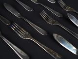 many forks and spoons laid out on a black table