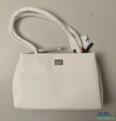 Le sac à main blanc est posé sur la table, à côté du sac blanc.