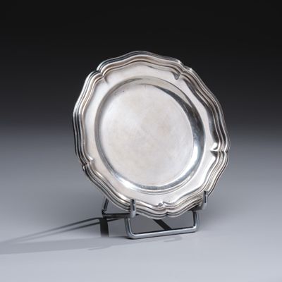 un plat ancien en argent posé sur un socle, sur une surface grise