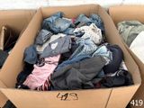 a cardboard box full of clothes sitting on the ground