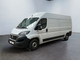 La camionnette blanche est garée dans une grande pièce au sol noir.