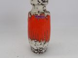 un vase rouge et blanc posé sur une surface blanche